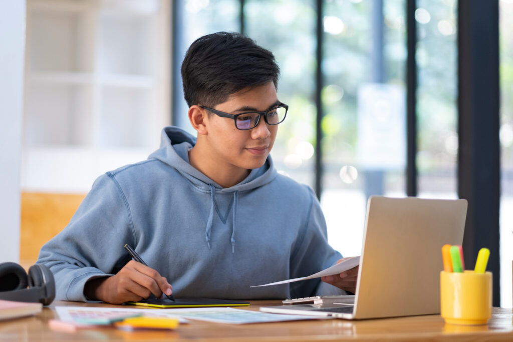 Young collage student using computer and mobile device studying online. Education and online learning.